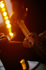 Close up look of a man playing the electric guitar during a concert, no faces are shown, shallow depth of field