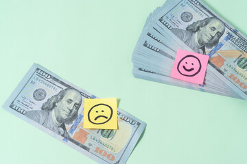 Sad and smile emoji with a dollar banknote on light green background