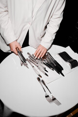 A waiter in white lays out forks and knives
