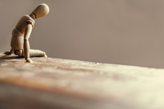Wooden mannequin reflecting on concepts of sadness and despair.