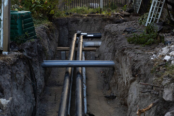 Construction workers install new underground pipes in a trench during late afternoon at a residential site in a suburban area