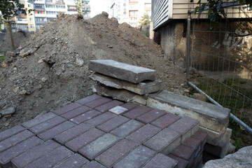 Construction site with stacked bricks and a dirt pile in an urban area during daylight hours