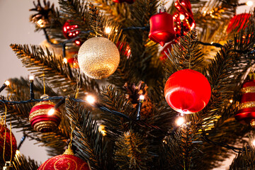 Closeup of a decorated artificial Christmas tree with festive red and gold ornaments, ideal for winter-themed projects, seasonal content, and holiday designs.
