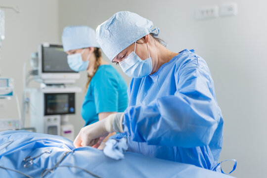 Two surgeons are focused on an operation in a sterile hospital environment, wearing surgical attire and masks. - Powered by Adobe