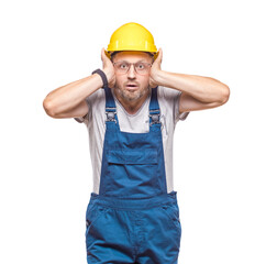 Angry middle-aged construction worker with hands on head and tearing hair out while looking to camera, isolated on white background. Craftsman against white wall