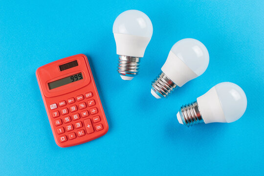 Energy Efficiency and Cost Calculation with LED Bulbs and Calculator on Blue Background