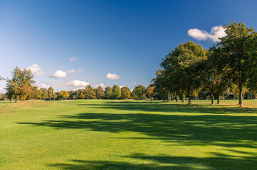 Golf fairway with autumn trees under clear blue sky