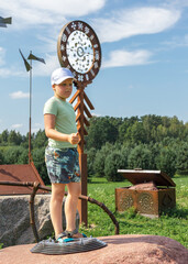 A little boy climbing a mountain and standing on a large rock poses and shows a like