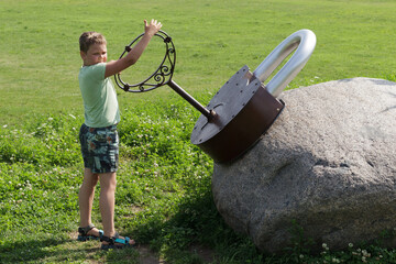 A boy and a gigantic lock with a large metal key in the park.