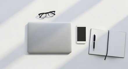 Overhead shot of a laptop, phone, glasses, and open notebook with a pen on a white surface