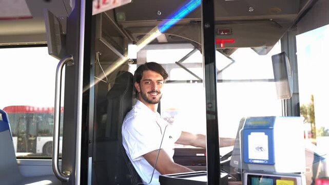 Friendly young male bus driver looking at the camera from his seat. Public transport professional on his daily city commuter route