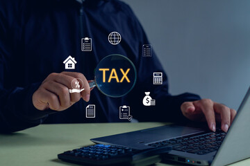 Businessman analyzing tax data with laptop and magnifying glass showing TAX text, symbolizing tax audit, financial review, digital accounting, and fintech innovation.