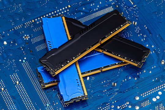 Four DDR memory chips in different colors lying on a blue printed circuit board.