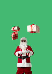 Santa Claus with a white curly beard, wearing a red suit and sunglasses, tosses gift boxes into the air against a green background. Ideal for Christmas-themed compositions and holiday layouts.