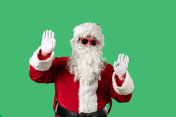 Santa Claus, with his white curly beard, red suit, and sunglasses, dances cheerfully against a green background. Ideal for Christmas themed compositions, advertising, and holiday layouts.