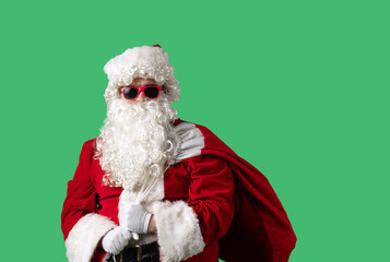 Santa Claus with a white curly beard, wearing a red suit and sunglasses, with a bag of gifts on a green background. Perfect for Christmas themed compositions, advertising, and holiday layouts.