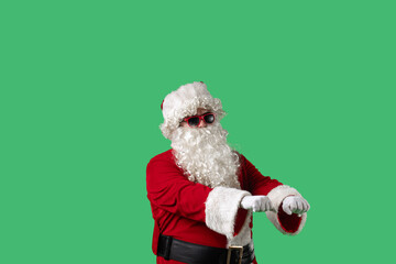 Santa Claus, with his white curly beard, red suit, and sunglasses, dances cheerfully against a green background. Ideal for Christmas themed compositions, advertising, and holiday layouts.
