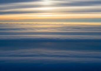 Fototapeta premium Aerial view of layered clouds at sunrise with golden light dawn