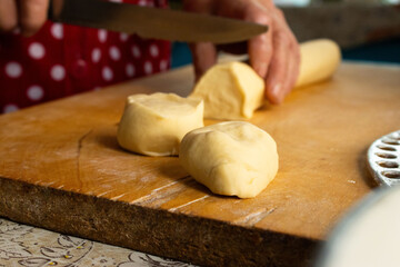 Close-up of Hands Using a Knife to Cut Raw Dough for Dumplings
