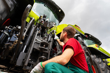 Agricultural technician repairing farm machinery outdoors © Barillo_Images
