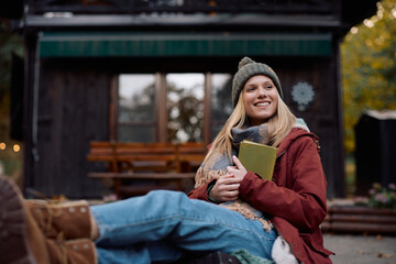 Young happy woman relaxing on porch in autumn day.