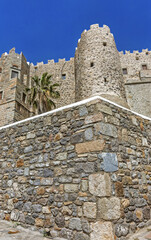 Historic stone fortress with cylindrical tower and crenellated walls surrounding the Monastery of Saint John the Theologian of Patmos, Greece.