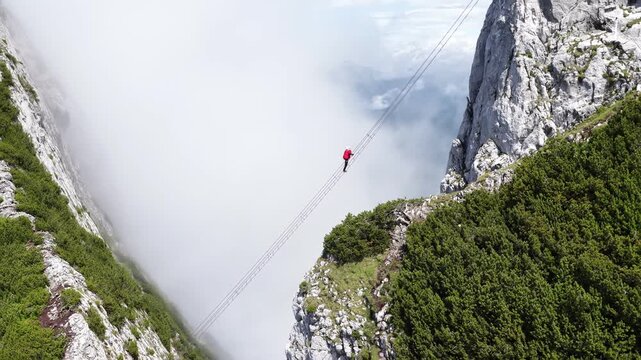 Aerial view of daring hiker crossing a suspension bridge in the mountains, Dachstein, Austria