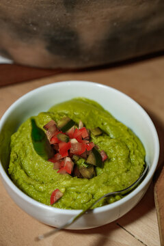 Green sprea of peas, decorated with chopped vegetables such as tomatoes and cucumbers.