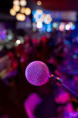 Close up of microphone in bar with blurred crowd in background.