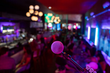 Close up of microphone in bar with blurred crowd in background.