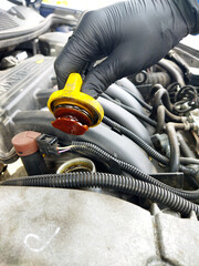 Mechanic checking coolant level in a vehicle engine compartment