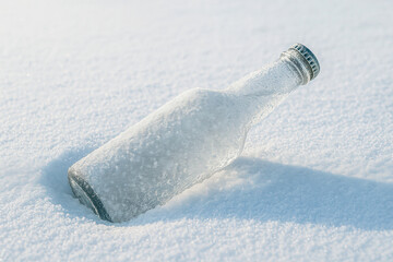A clear glass bottle half-buried in fresh white snow, glistening with frost crystals under bright sunlight. The minimalistic composition and cool tones emphasize isolation, purity, winter stillness