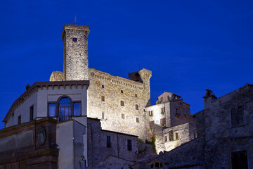 Stone walls of a medieval castle with a tower at night in Bolsena