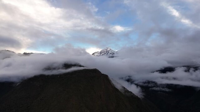Cinematic aerial footage of the drone moving forward into cloud cover which clears to dramatically reveal the majestic, snow-capped Mount Salkantay (6,271 meters) in the Peruvian Andes