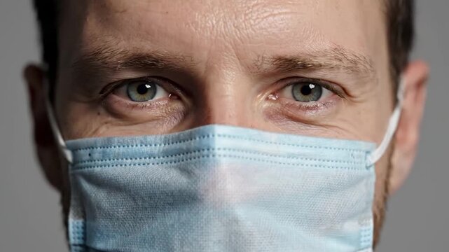 Person in medical mask close up portrait with focused eyes showing protection health safety hygiene and disease prevention