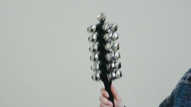 vivid closeup showcasing hand shaking metal jingle bells with rhythmic motion and lively sound