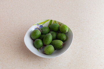 Fresh Green Feijoa Fruits in a White Bowl on Light Background