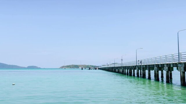 timelaspe 4k video at docking boats pier at tropical coean sea shore bank with calm sea ocean bay and sunshine cloudy background.tropical harbour landscape with blue sky and white cloud background