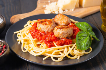 Delicious spaghetti with tasty meatballs in tomato sauce, and basil on background. Restaurant menu.