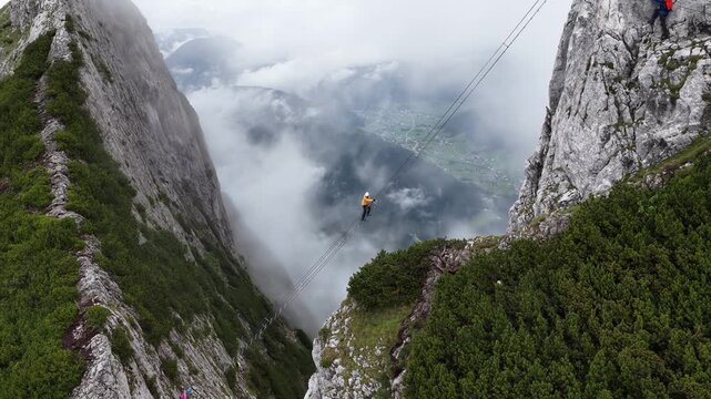 Aerial view of a climber crossing ladder bridge between mountain peaks, Dachstein, Austria