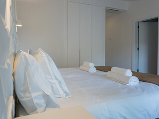 Elegant bedroom with crisp white linens, fluffy pillows, and neatly folded towels, offering comfort...