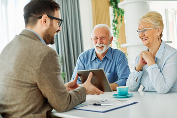 Senior couple having a meeting with an agent using a tablet computer , businessman, salesperson or doctor in his office