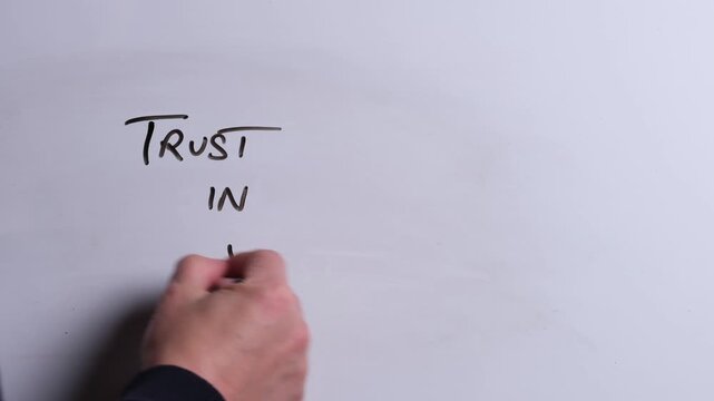 A person is writing Trust in Jesus in black marker pen on a whiteboard, perfect for Christian, religious themes, Church communications or faith presentations