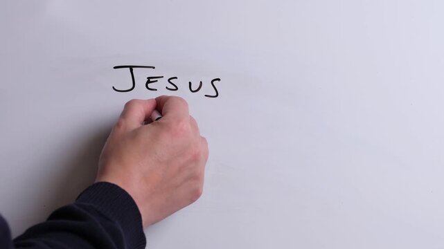 A person is writing Jesus Loves You in black marker pen on a whiteboard, perfect for Christian, religious themes, Church communications or faith presentations