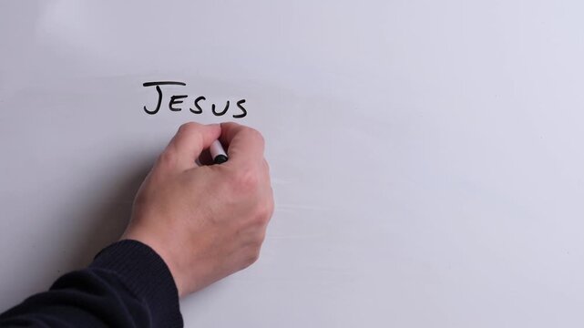 A person is writing Jesus is Life in black marker pen on a whiteboard, perfect for Christian, religious themes, Church communications or faith presentations