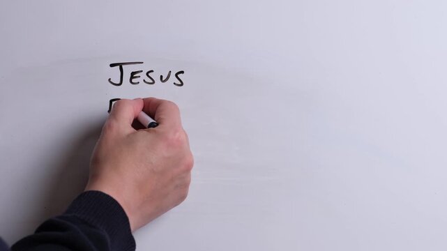 A person is writing Jesus Brings Peace in black marker pen on a whiteboard, perfect for Christian, religious themes, Church communications or faith presentations