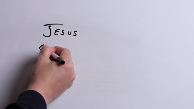A person is writing Jesus Conquered Death in black marker pen on a whiteboard, perfect for Christian, religious themes, Church communications or faith presentations