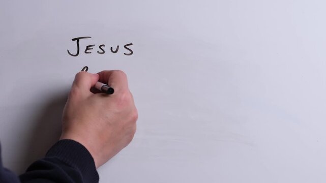 A person is writing Jesus Reigns Forever in black marker pen on a whiteboard, perfect for Christian, religious themes, Church communications or faith presentations