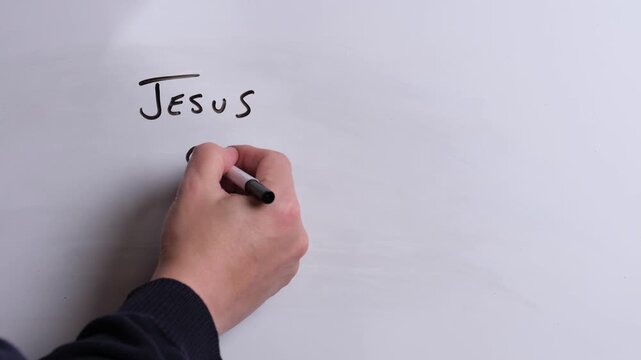 A person is writing Jesus Gives Grace in black marker pen on a whiteboard, perfect for Christian, religious themes, Church communications or faith presentations