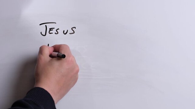 A person is writing Jesus Restores Hope in black marker pen on a whiteboard, perfect for Christian, religious themes, Church communications or faith presentations